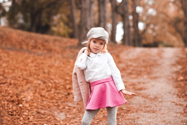 Elegante bambina che indossa abiti autunnali in posa nel parco