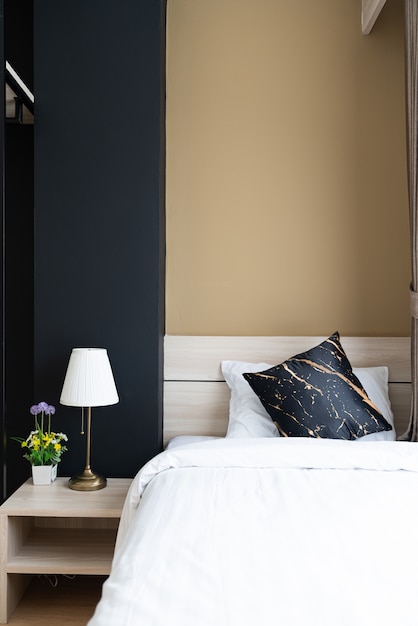 Elegante camera da letto ad angolo con testiera in legno con morbidi cuscini con pareti dipinte di blu navy e giallo