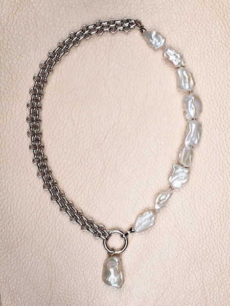 Elegante collana di perle barocche di lusso con pendente su fondo in pelle beige. Primo piano