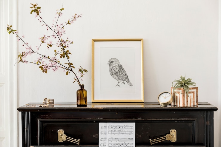 Foto elegante composizione all'interno del soggiorno con pianoforte nero, cornice per poster finta oro, fiori primaverili, decorazione, orologio e accessori personali alla moda nell'arredamento moderno della casa.