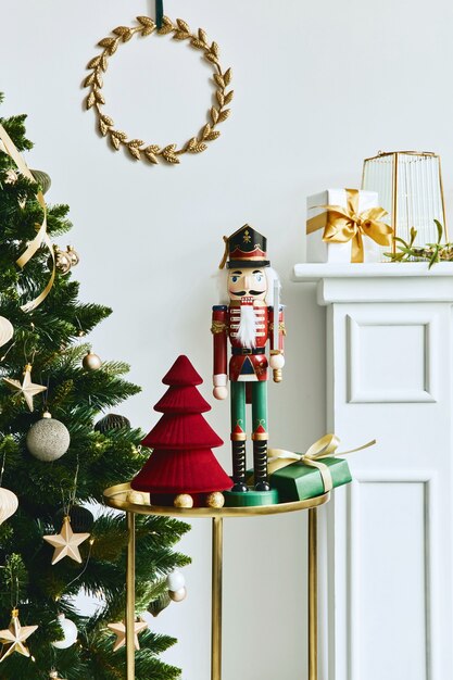 Elegante composizione natalizia all'interno del soggiorno con camino bianco, albero di Natale e corona, stelle, regali e decorazioni. Babbo Natale sta arrivando. Modello.