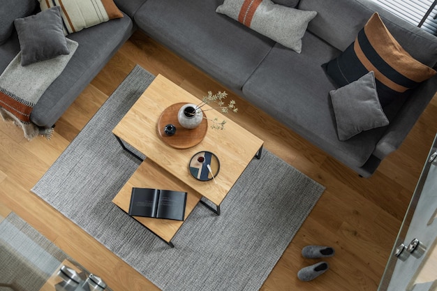 Elegante composizione vista dall'alto dell'interno del soggiorno con divano ad angolo grigio tavolino da caffè e accessori personali minimalisti Arredamento moderno per la casa Modello di pavimento in parquet