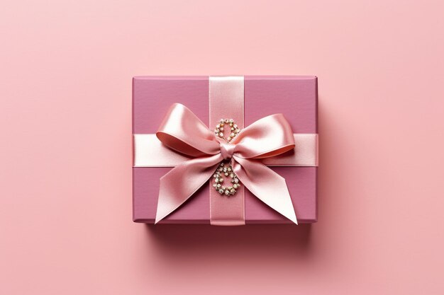 Elegante confezione regalo rossa splendidamente ornata da un nastro di raso dorato su sfondo rosa pastello
