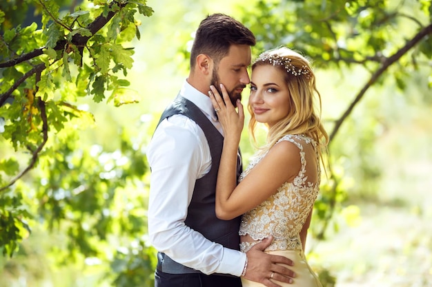 Elegante coppia di sposi felici che posano nel parco il giorno delle nozze. Coppia perfetta sposa sposo in posa