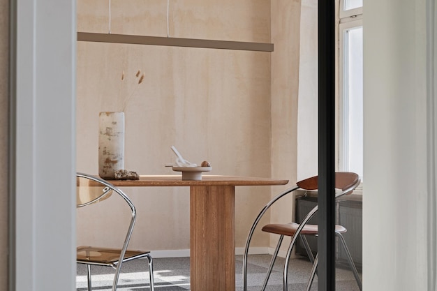 Elegante design degli interni della spaziosa sala da pranzo con tavolo da pranzo in legno, poltrone e bellissimi accessori personali. Arredamento moderno per la casa. Parete della struttura. Ispirazione minimalista rustica. Modello.