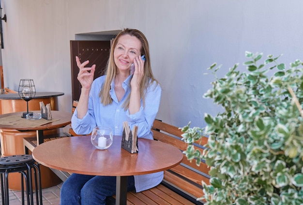 Elegante donna anziana che usa lo smartphone mentre è seduto sulla terrazza del caffè all'aperto in città Concetto di utilizzo delle moderne tecnologie da parte degli anziani