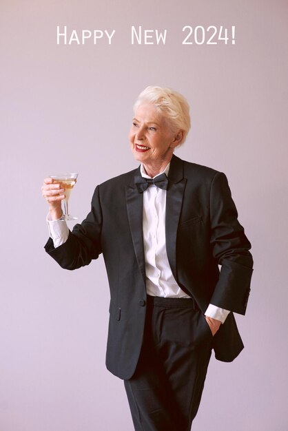 elegante donna anziana matura in smoking con un bicchiere di spumante che celebra la festa divertente del nuovo anno