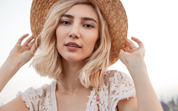 Elegante donna bionda che regola il cappello in natura