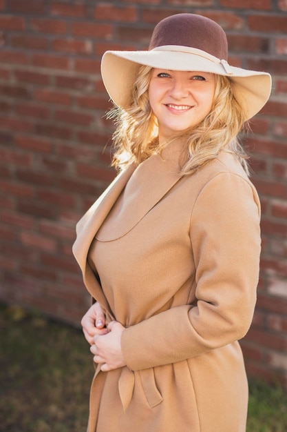 Elegante donna bionda in cappotto e cappello