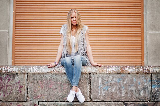 Elegante donna bionda indossare jeans e ragazza senza maniche con camicia bianca