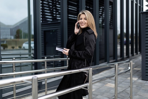 Elegante donna d'affari caucasica adulta che parla al telefono cellulare all'ingresso del centro business