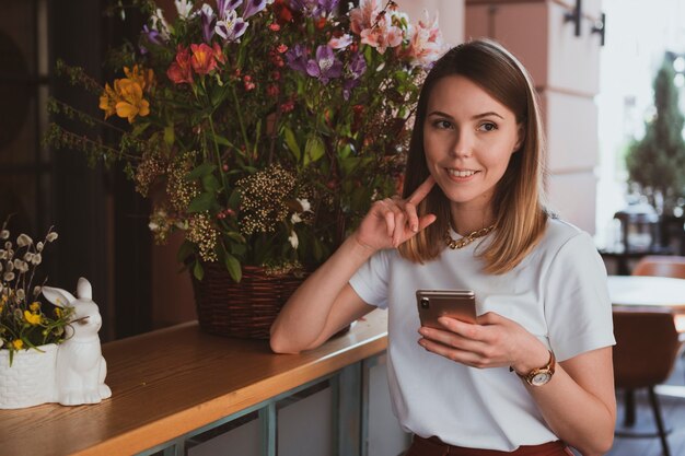 Elegante donna d'affari con smartphone al negozio di fiori