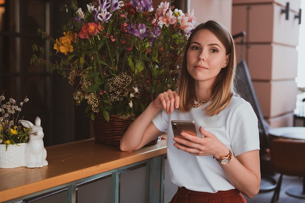 Elegante donna d'affari con smartphone al negozio di fiori