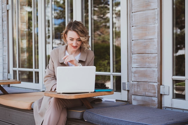 Elegante donna d'affari in un caffè di strada che lavora al computer portatile