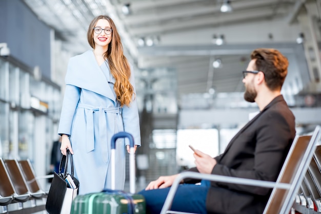 Elegante donna d'affari nel cappotto che incontra l'uomo d'affari nella sala d'attesa dell'aeroporto