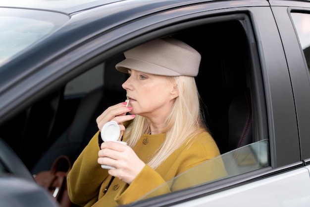Elegante donna di mezza età che mangia gomma da masticare in un'auto al volante