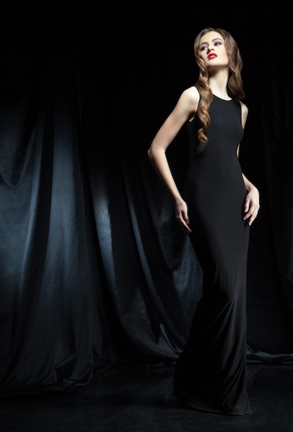 Elegante donna in abito nero con braccia sui fianchi