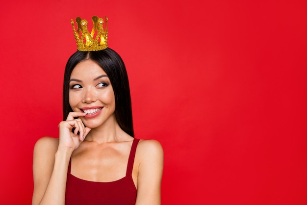 Elegante donna in abito rosso in posa contro il muro rosso