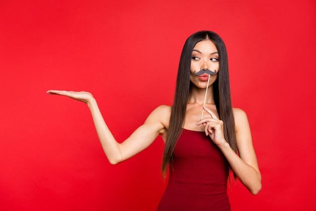 Elegante donna in abito rosso in posa contro il muro rosso