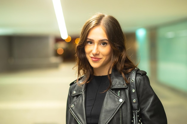 Elegante donna in giacca di pelle in piedi nel parcheggio