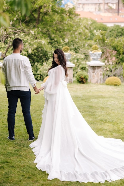 Elegante donna incinta in abito bianco di lusso che cammina con il suo bel marito