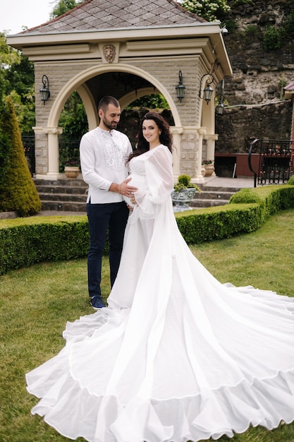 Elegante donna incinta in abito bianco di lusso che cammina con il suo bel marito