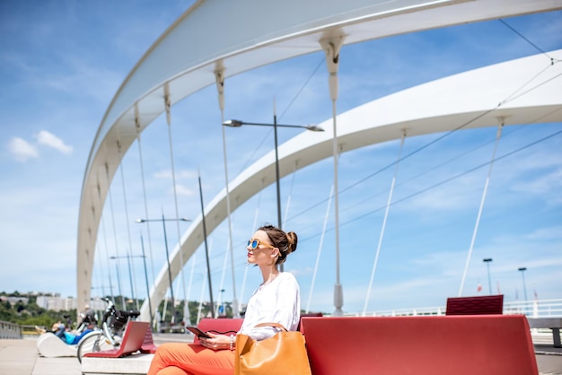 Elegante donna seduta sul ponte moderno nella città di Lione