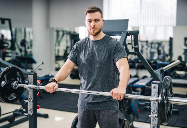 Elegante e bello trainer in palestra moderna Attraente giovane in attesa di allenarsi in palestra