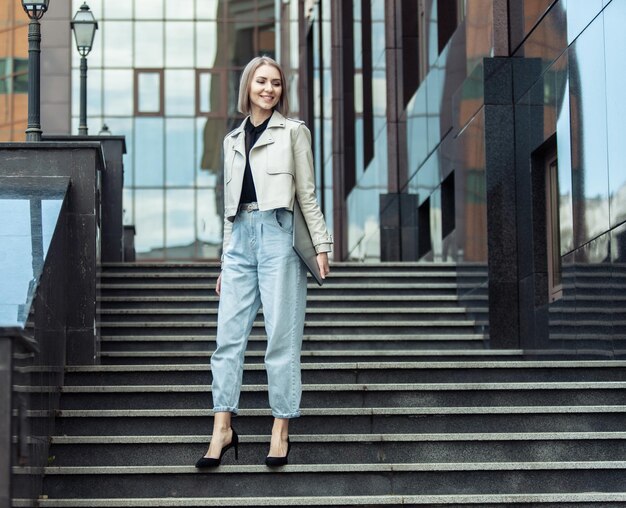 Elegante e moderna donna d'affari con un computer portatile in mano sui gradini vicino al centro business Stile di vita