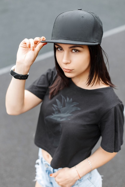 Elegante giovane bella ragazza in un berretto nero e una maglietta.