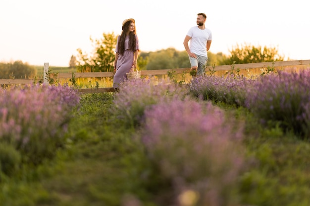 Elegante giovane coppia adulta che cammina al campo di lavanda con un appuntamento romantico