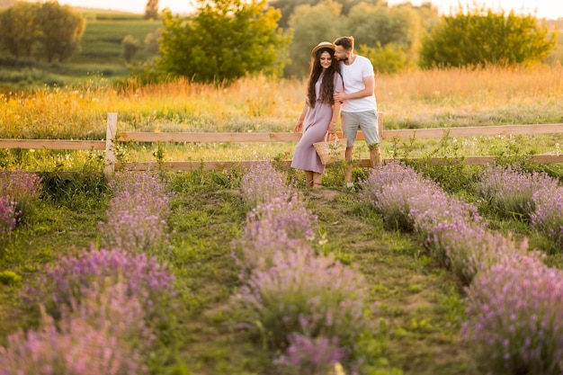 Elegante giovane coppia adulta che cammina al campo di lavanda con un appuntamento romantico