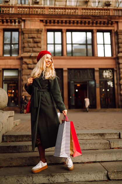 Elegante giovane donna in abiti alla moda con borse della spesa dopo lo shopping Autunno shopping