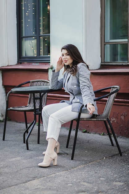 Elegante giovane donna in giacca in posa in caffè e sorriso della città