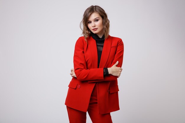 Elegante giovane donna in un bel vestito rosso giacca pantaloni pantaloni camicetta nera su sfondo bianco