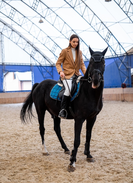 Elegante giovane donna in uniforme da fantino Bella signora equitazione coperta