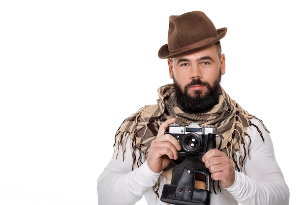 Elegante giovane fotografo maschio con fotocamera retrò scatta foto su sfondo bianco