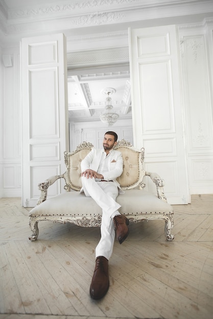 Elegante giovane uomo bello con la barba in un abito classico bianco