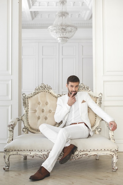 Elegante giovane uomo bello con la barba in un abito classico bianco