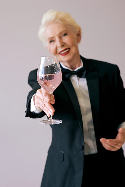 elegante matura sommelier donna anziana in smoking con un bicchiere di vino