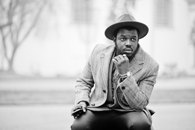 Elegante modello uomo afroamericano in giacca grigia con cravatta e cappello rosso Foto in bianco e nero