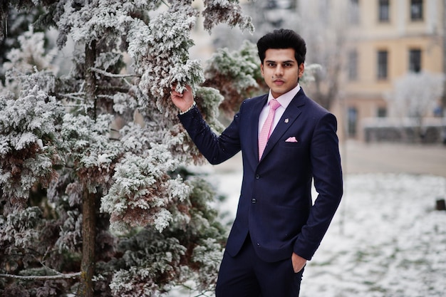 Elegante modello uomo macho indiano su abito e cravatta rosa in posa in una giornata invernale