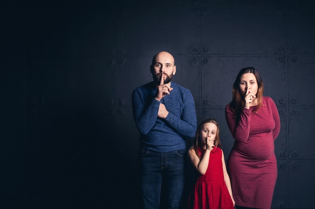 Elegante padre di famiglia, madre, figlia mostrano shh