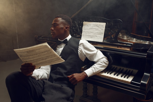 Elegante pianista a coda in ebano, performance jazz in un club. l'esecutore posa allo strumento musicale prima di suonare la melodia