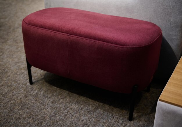 Elegante pouf o poggiapiedi lungo in velluto rosso nella sala espositiva di un negozio di mobili