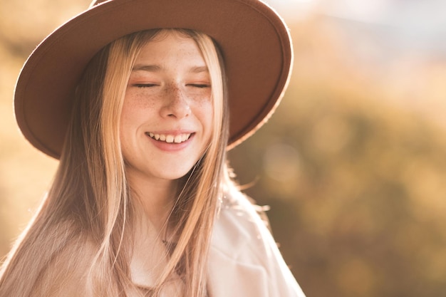 Elegante ragazza adolescente che indossa cappello e cappotto invernale su sfondo naturale