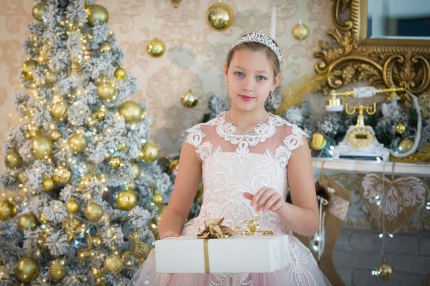 Elegante ragazza all'albero di Capodanno con un regalo Bambino a Natale