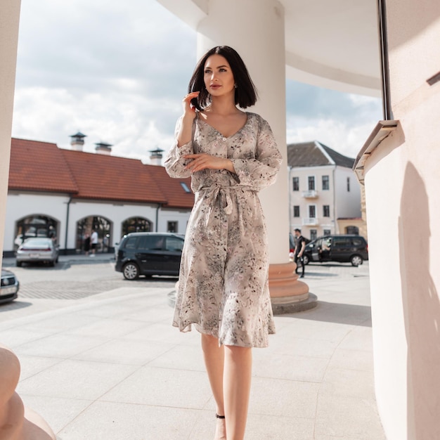 Elegante ragazza carina in abito primaverile eleganza moda cammina per strada vicino a un edificio d'epoca