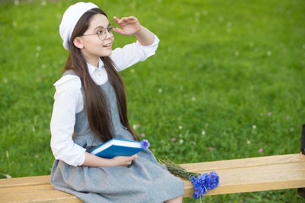 Elegante scolara bambino ragazza lettura libro nel parco, concetto di scuola d'elite.