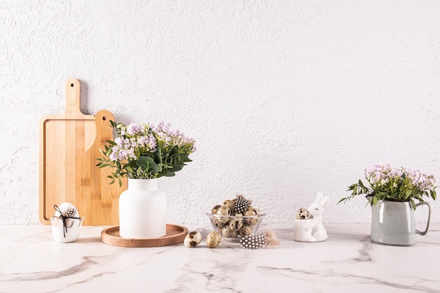 Elegante sfondo da cucina per il giorno di Pasqua con vasi di fiori primaverili lilla ciotola con uova di quaglia Prodotti naturali cucina ecologica